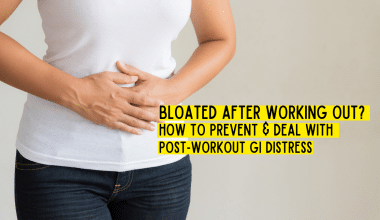 Woman holding stomach in t-shirt and jeans - bloated after a workout