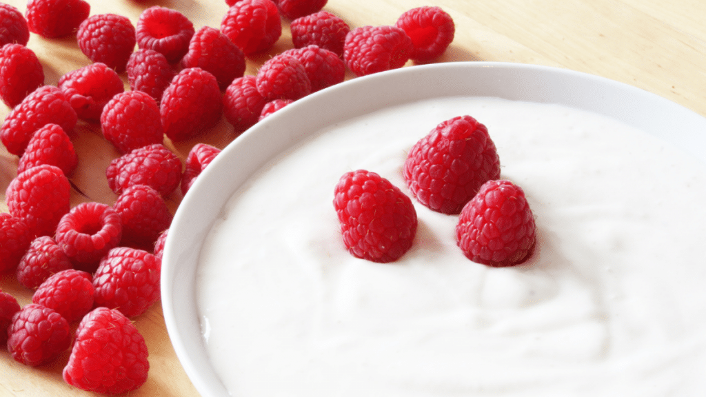 raspberries and yogurt in a bowl - foods to eat to help bloating after a workout 