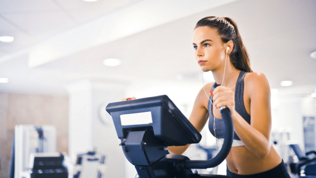 Woman working out on elliptical at gym showing proper breathing  