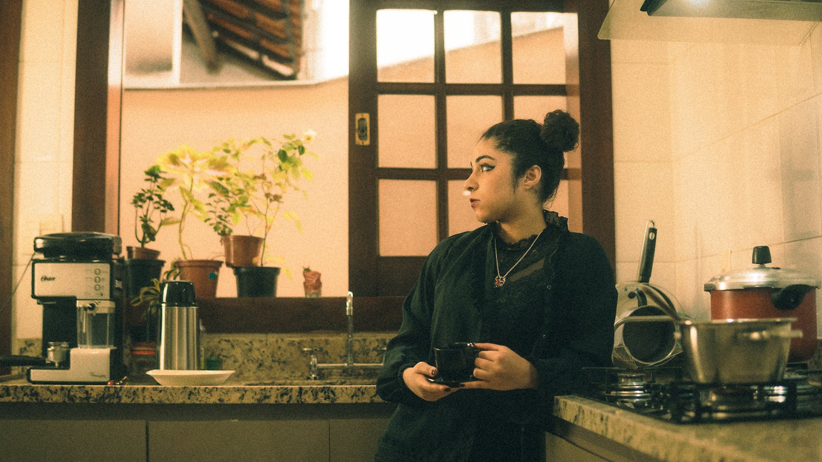 Woman standing in kitchen holding a cup of coffee warm morning